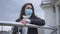 Portrait of desperate frustrated young Caucasian woman in coronavirus face mask standing outdoors at handrails thinking