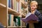 portrait of diligent caucasian child boy with book between bookshelves in campus library