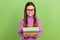 Portrait of diligent intelligent schoolgirl dressed pullover in glasses hold book prepare for exam  on green
