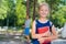 Portrait of a diligent schoolgirl with a backpack and a book goes to first grade. Mom sends a happy daughter to