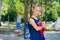 Portrait of a diligent schoolgirl with a backpack and a book goes to first grade. Mom sends a happy daughter to