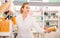 Portrait of diligent smiling pleasant positive female druggist in white coat working in pharmacy