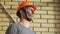 Portrait Dirty Building Worker on Background Brick Wall. Handsome Caucasian Serious Man in a Hard Hat. People Working Equipment