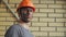 Portrait Dirty Building Worker on Background of a Brick Wall. Handsome Serious Man in a Hard Hat. Filthy Job and Physical labor