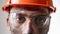 Portrait dirty tired male builder in work helmet and glasses looks camera