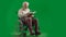 Portrait of disabled man isolated on chroma key green screen full shot. Senior bearded man in wheelchair holding