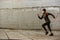 Portrait of disabled sportswoman with prosthetic leg in tracksuit, running outdoor along concrete wall