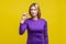 Portrait of disappointed woman showing a little bit gesture. indoor studio shot isolated on yellow background