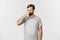 Portrait of disgusted caucasian man in gray t-shirt, shut his nose from awful smell, standing over white background