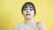 Portrait of the distorted girl with capricious emotion on yellow background 4K