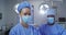 Portrait of diverse male and female surgeon wearing face masks standing in operating theatre