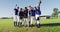 Portrait of diverse team of female baseball players and coach on pitch, raising fists and cheering