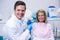 Portrait of doctor holding dental mold while sitting by patient