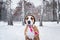 Portrait of a dog in winter knit hat outdoors in snow.