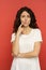 Portrait of doubtful young italian female pensive think with folded arms over red studio background