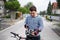 Portrait of down syndrome adult man with bicycle standing outdoors on street.