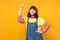 Portrait of dreamful girl teenager in french beret, denim sundress pointing index finger up isolated on yellow wall
