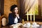 Portrait of Dreaming Caucasian Brunette Woman Posing in Retro Style Dress With Coffeepot and Jam At The Table Indoors