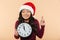 Portrait of dreaming girl in Santa Claus red hat holding clock s