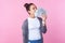 Portrait of dreamy brunette teen girl standing with her eyes closed and happy satisfied face, sniffing dollars. pink background