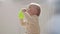 Portrait drinking baby at home. Child learns to drink on his own. Kid sitting on floor with plastic green cup in hands