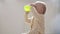 Portrait drinking baby at home. Child learns to drink on his own. Kid sitting on floor with plastic green cup in hands