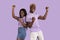 Portrait of ecstatic black couple celebrating success, gesturing YES and shouting in excitement, lilac studio background