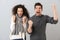 Portrait of ecstatic couple man and woman screaming while clenching fists, isolated over gray background