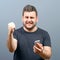 Portrait of ecstatic man holding cell phone and celebrating with closed fist against gray background