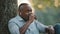 Portrait elderly African man sitting under tree, entrepreneur resting in park. Adult mature smiling retired person