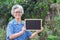 Portrait of an elderly Asian woman with short gray hair, holding a blackboard, smiling, and looking at the camera while standing