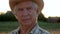 Portrait of an elderly caucasian farmer agronomist in a cowboy hat on the field