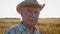 Portrait of an elderly caucasian farmer agronomist in a cowboy hat on the field