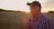 Portrait of an elderly farmer in a cap at sunset in a field of wheat sniffing brush rye. Enjoy the aroma of cereal