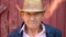 Portrait of an elderly farmer in a straw hat on a farm background. Face of a man in age