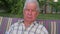 Portrait of an elderly and gray-haired man with deep wrinkles on his face.