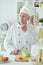 Portrait of elderly male chef cooking at kitchen