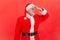 Portrait of elderly man with gray beard wearing santa claus costume feeling awful bad smell, keeping fingers on nose, disgusting