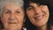 Portrait of elderly woman with her adult daughter looking into camera and showing joyful emotions. Happy women smiling
