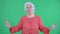 Portrait elderly woman looking at the camera and smiling. Gray haired grandmother in red blouse on green screen at