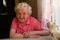 Portrait of an elderly woman pensioner sitting at a table in the kitchen in his house.