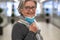 Portrait of elderly woman taking off the surgical mask due to coronavirus standing in deserted mall. Attractive smiling senior