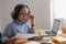 Portrait of an elderly woman working inside the house using laptops and tablets to work and check important documents for