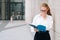 Portrait of an elegant brooding business lady girl in glasses holds a folder with documents