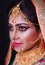 Portrait of an elegant Indian model in Bridal look with heavy gold jewelry and red sari . Bengali bride