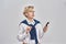 Portrait of elegant middle aged caucasian woman wearing business attire and earphones holding smartphone, looking away