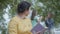Portrait of an elegant senior woman reading the book in the park in the foreground. Blurred figures of two