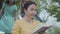 Portrait of an elegant senior woman reading the book in the park in foreground. Two girls sneaking up behind, one