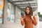 Portrait of elegant young Asian woman holding shopping bags and using smartphone on the go while leaving mall