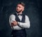 Portrait of an elegantly dressed young man in a vest with bow tie posing with his arms crossed and looking sideways